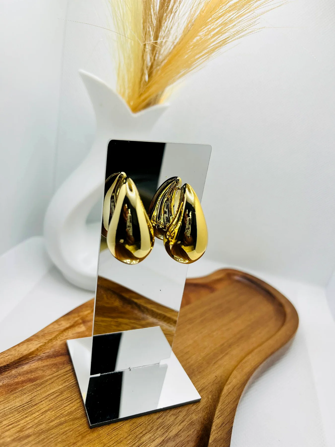 Gold hoop earrings styled on a display stand